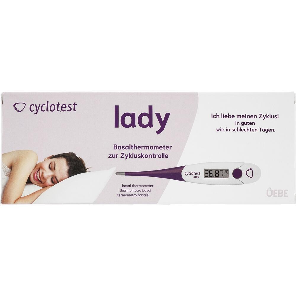 Eine Frau liegt lächelnd neben einem lila Basalthermometer zur Zykluskontrolle.